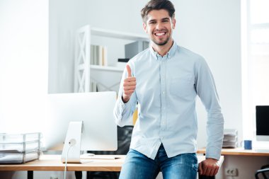 Ofiste başparmak gösterilmesini neşeli genç işadamı