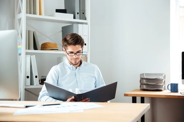 Koncentrerad ung affärsman arbetar med dokument i mappen — Stockfoto