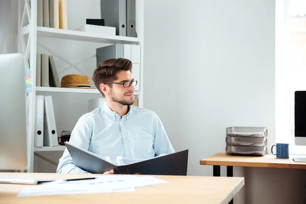 Fundersam ung affärsman holding mapp med dokument och tänkande — Stockfoto