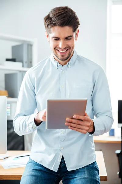 Ευτυχισμένος όμορφος νεαρός επιχειρηματίας εργασίας και χρησιμοποιώντας tablet — Φωτογραφία Αρχείου