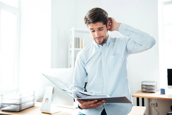 Pensiero giovane uomo d'affari guardando attraverso i documenti in ufficio — Foto Stock