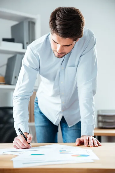 Allvarlig ung affärsman skriva på bordet i office — Stockfoto