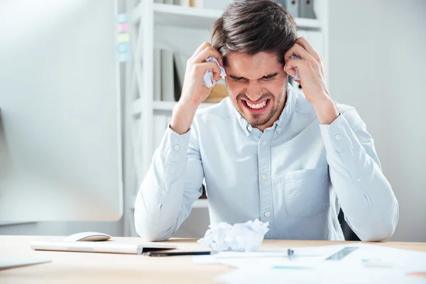 Agressieve boos zakenman bedrijf verfrommeld papier zit op werkplek — Stockfoto