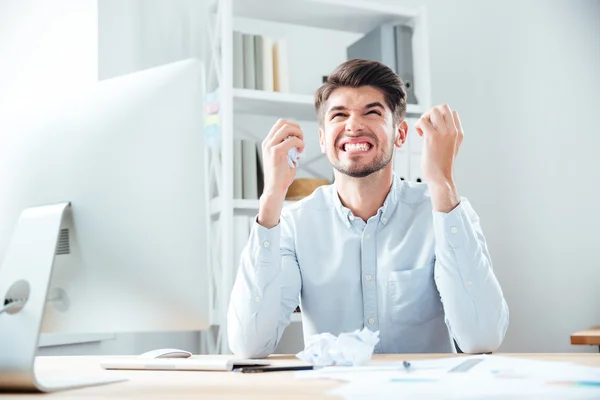 Loco empresario irritado sosteniendo papel arrugado y trabajando en el lugar de trabajo —  Fotos de Stock