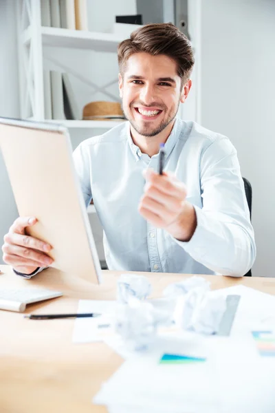 Fröhlicher junger Geschäftsmann, der Ihnen Notizblock und Stift schenkt — Stockfoto