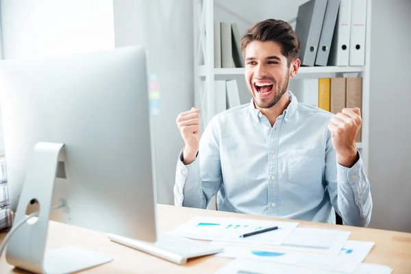 Feliz joven empresario emocionado sentado y celebrando el éxito —  Fotos de Stock