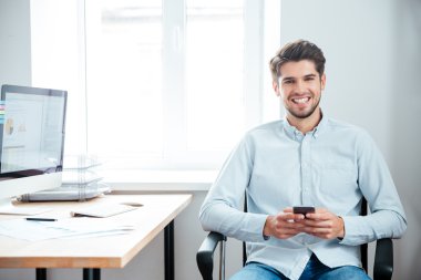 Masada oturan ve akıllı telefon kullanma office iş adamı