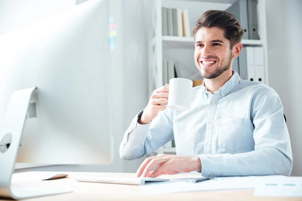 Молодой бизнесмен в повседневной одежде пьет кофе в офисе — стоковое фото