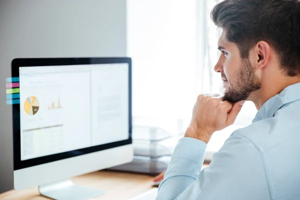 Sidovy av ung självsäker affärsman med laptop i office — Stockfoto