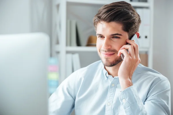 Zakenman zittend op zijn werkplek op kantoor met mobiele telefoon — Stockfoto