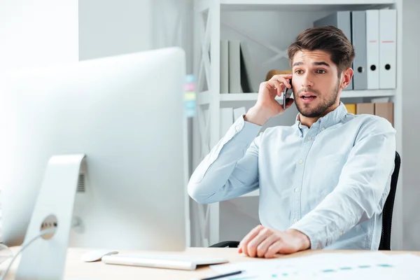 Porträt eines überraschten Geschäftsmannes, der mit seinem Handy im Büro telefoniert — Stockfoto