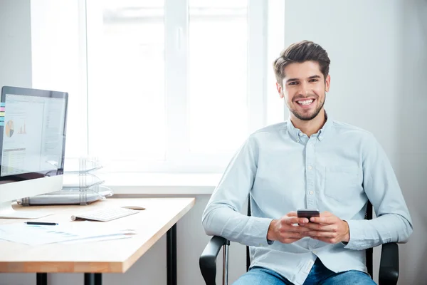 Masada oturan ve akıllı telefon kullanma office iş adamı — Stok fotoğraf