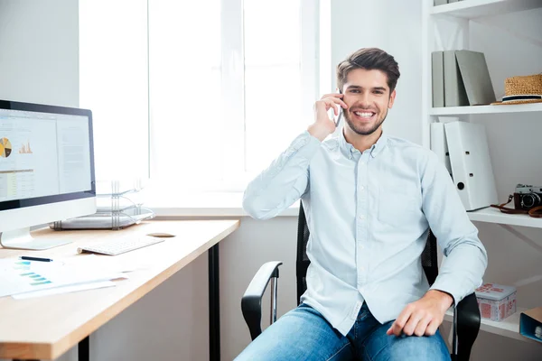 Бізнесмен сидить на своєму робочому місці в офісі з мобільним телефоном — стокове фото