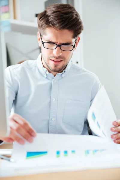 Homme d'affaires assis sur la table et lisant un document au bureau — Photo