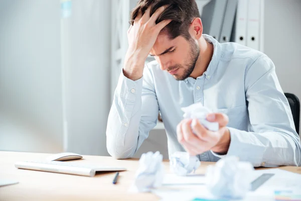 Exhausted stressed young man crumpling paper at workplace — Stock Photo, Image