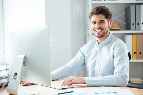 Uomo d'affari che utilizza il computer portatile in ufficio e guardando la fotocamera — Foto Stock