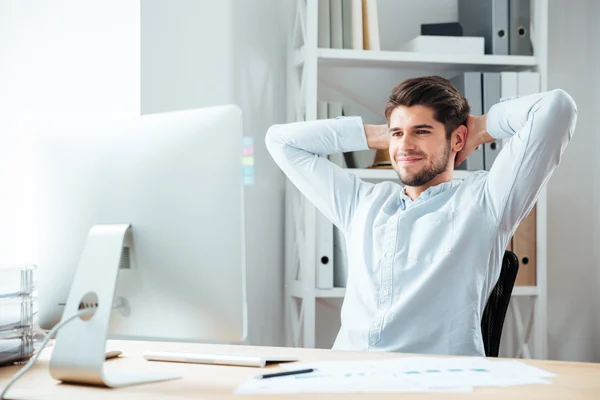 Hombre de negocios alegre sentado en la mesa con el ordenador portátil y estiramiento — Foto de Stock