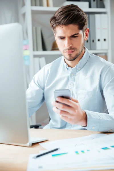 Pengusaha duduk di meja dan menggunakan smartphone di kantor — Stok Foto