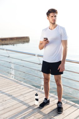 Ayakta ve cep telefonu açık havada kullanma yakışıklı spotrsman