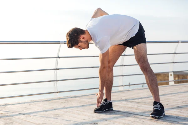 Atleta masculino fazendo exercícios matinais no terraço de madeira — Fotografia de Stock