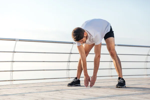 Hombre atleta estiramiento y calentamiento antes de trotar en la mañana —  Fotos de Stock
