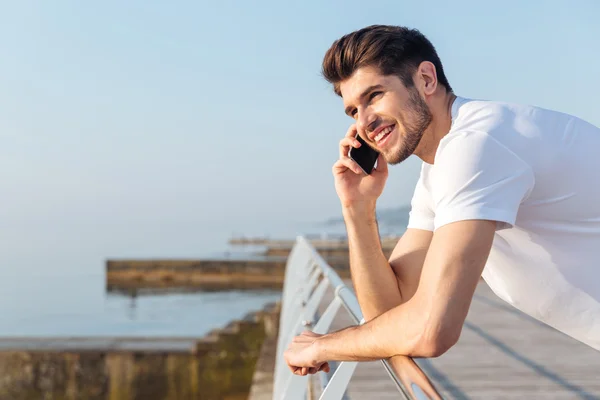 Szczęśliwy młody człowiek rozmowy na telefon komórkowy na zewnątrz — Zdjęcie stockowe