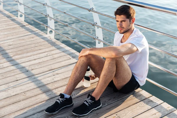 运动员与瓶水坐，放松在码头上 — 图库照片