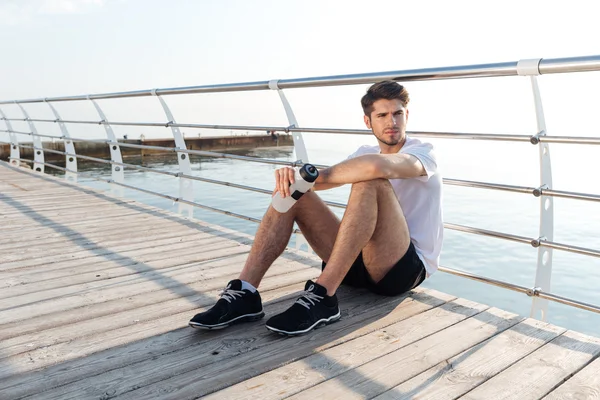 Fatigué jeune sportif assis et relaxant — Photo