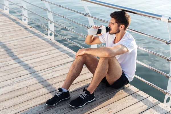 Pier és ivóvíz ül férfi atléta — Stock Fotó