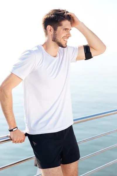 Guapo joven deportista descansando en el muelle después del entrenamiento — Foto de Stock