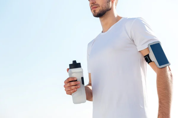 Imagem recortada de um desportista masculino segurando garrafa de água ao ar livre — Fotografia de Stock