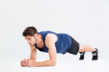Focused handsome young sportsman doing plank core exercise clipart