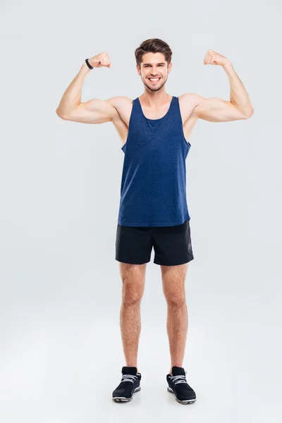 Retrato de cuerpo entero de un hombre sonriente mostrando sus bíceps —  Fotos de Stock