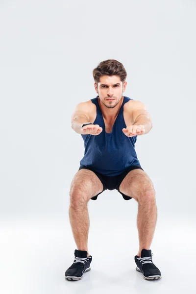 Handsome young sportsman doing squats — Stock Photo, Image