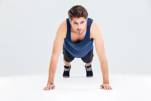 Красивый молодой человек спортсмен тренируется и делает упражнения на доске — стоковое фото