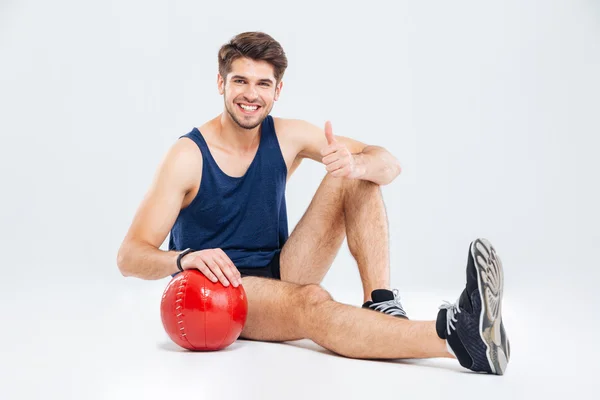 Glad Sportsman med röd boll sitter och visar tummen upp — Stockfoto