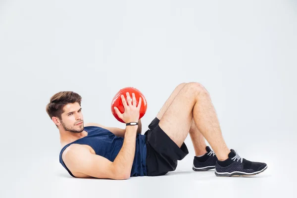 Attractive jovem desportista segurando bola vermelha e fazendo crunches — Fotografia de Stock