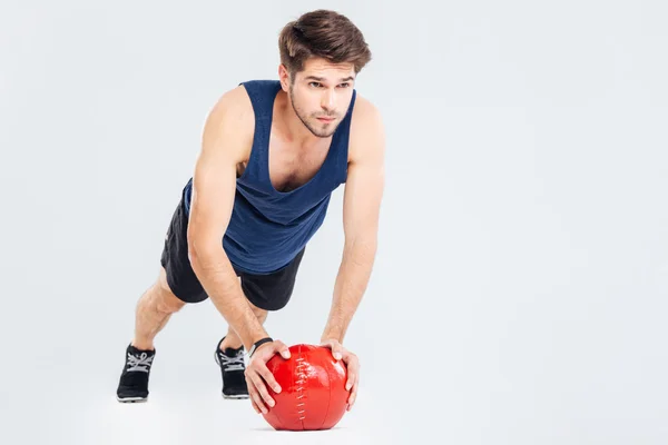 Όμορφος νέος άνθρωπος αθλητής κάνει push ups στην κόκκινη μπάλα — Φωτογραφία Αρχείου