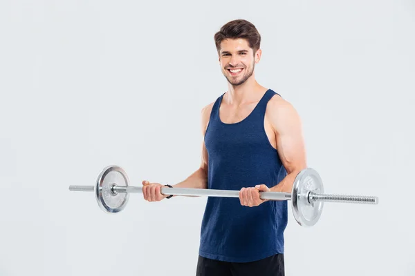 Jovem desportista alegre de pé e levantar barbell — Fotografia de Stock