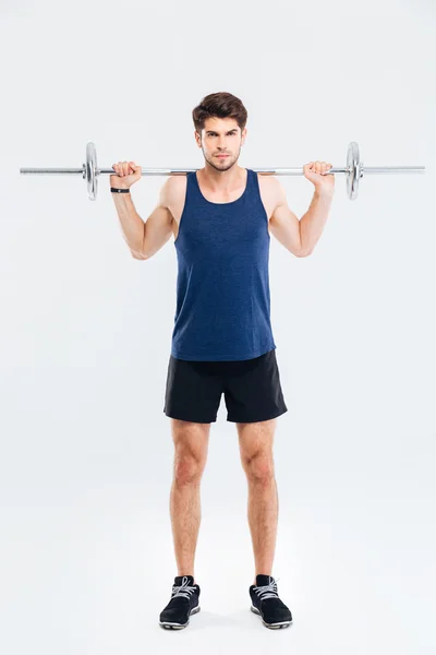 Сконцентрированный молодой спортсмен, стоящий и тренирующийся с штангой — стоковое фото