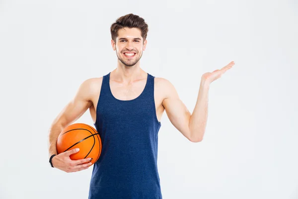 Cheerul young sportsman with basketball ball holding copyspace on palm — Stock Photo, Image