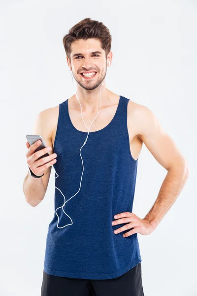 Χαμογελαστός νεαρός αθλητής να ακούτε μουσική με κινητό τηλέφωνο — Φωτογραφία Αρχείου