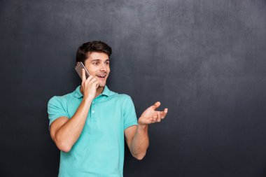 Gülümseyen çekici genç adam ayakta ve cep telefonu konuşuyor