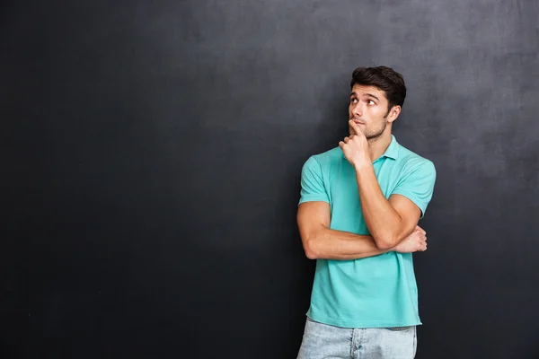 Pensive handsome young man standing with hands folded and thinking — Stock Photo, Image