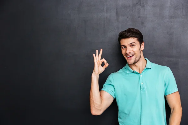 Glad ung man i blå t-shirt visar tummen upp — Stockfoto