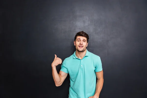 Sonriente joven feliz apuntando con el dedo hacia arriba — Foto de Stock