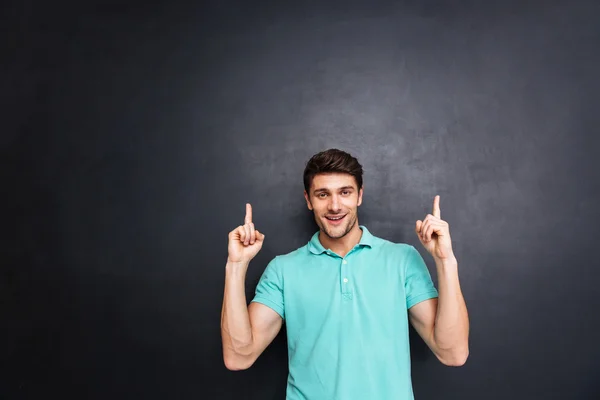 Sonriente joven feliz apuntando hacia arriba con ambas manos — Foto de Stock