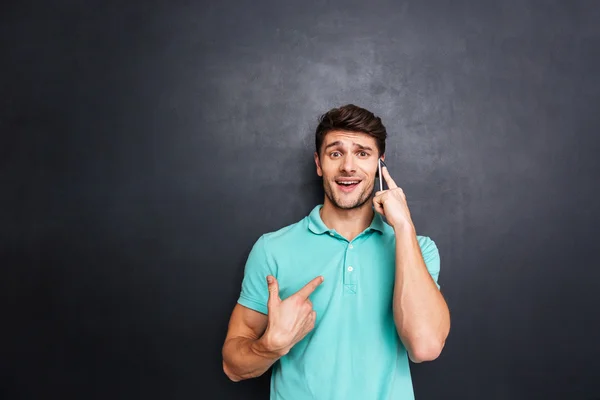 Förvirrad ung man talar i mobiltelefon över vit bakgrund — Stockfoto
