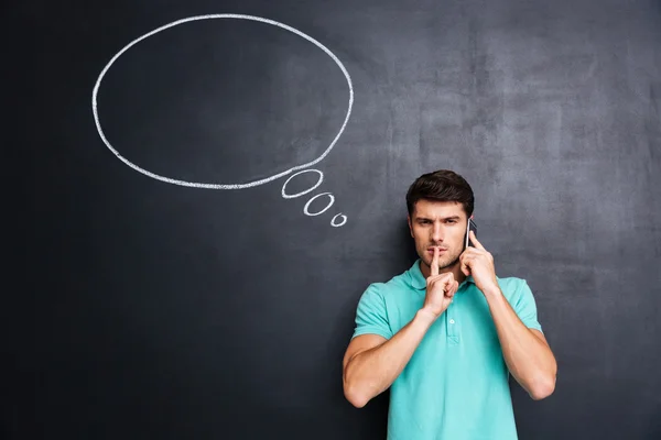 Man talking on cell phone and showing silence gesture — Stock Photo, Image