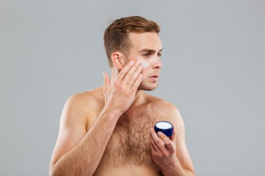 Genç adam krem losyon yüzüne koydu